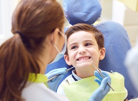 A young boy smiling while looking at his emergency dentist in Covina