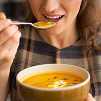 young woman eating soup after getting dental implants in Covina
