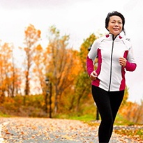 woman jogging though a park in autumn 