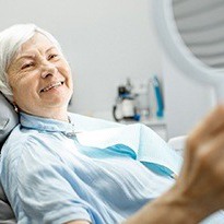 elderly woman admiring her smile in the mirror 