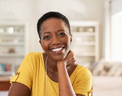 Woman in yellow shirt smiling at home
